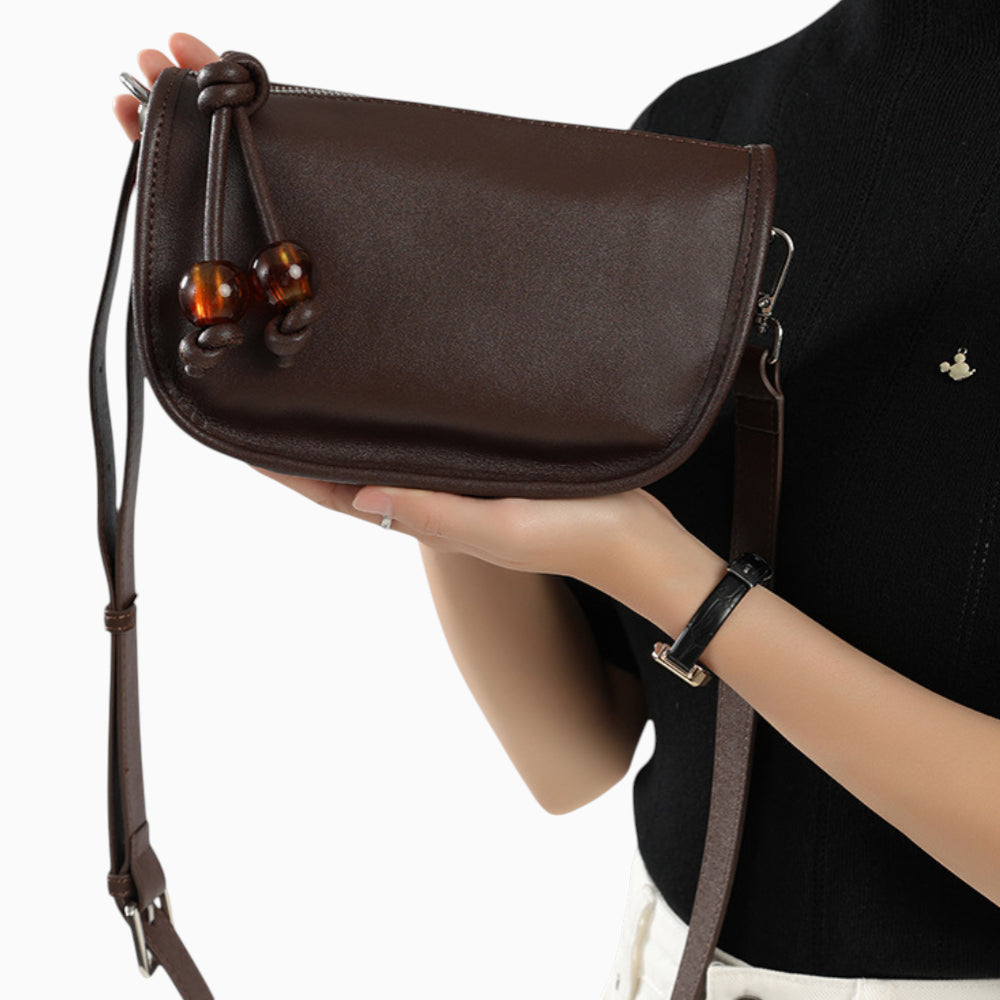 Sac bandoulière en cuir marron pour femme, modèle compact horizontal Manon, porté sur un mannequin.