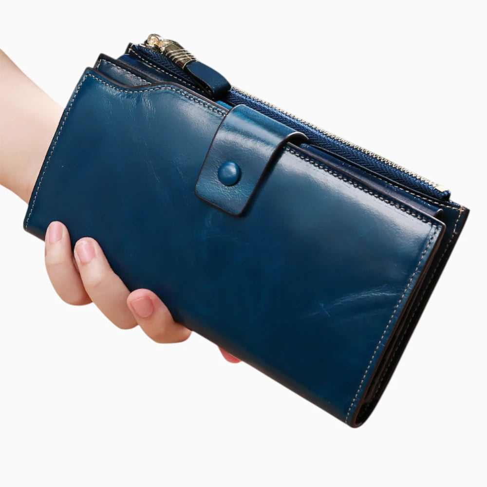 Portefeuille cuir bleu femme avec bouton pression et fermeture zip tenu en main