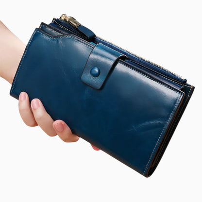 Portefeuille cuir bleu femme avec bouton pression et fermeture zip tenu en main