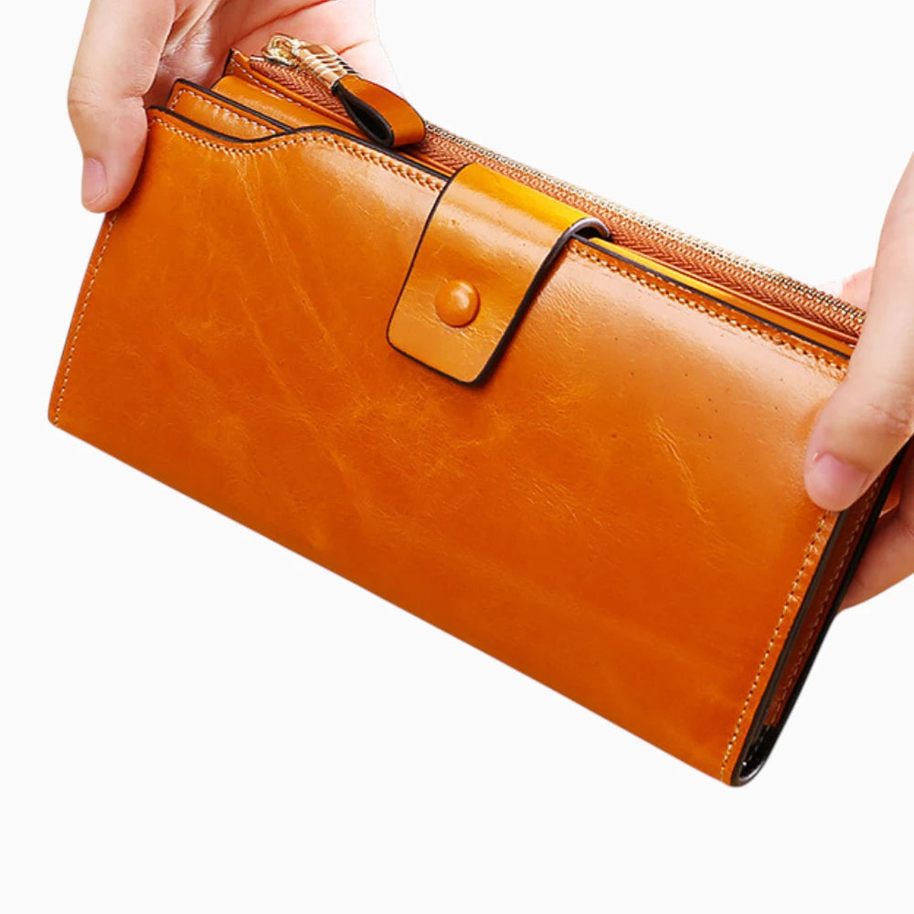Portefeuille cuir caramel femme avec bouton pression et fermeture zip tenu en main