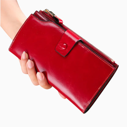 Portefeuille cuir rouge femme avec bouton pression et fermeture zip tenu en main